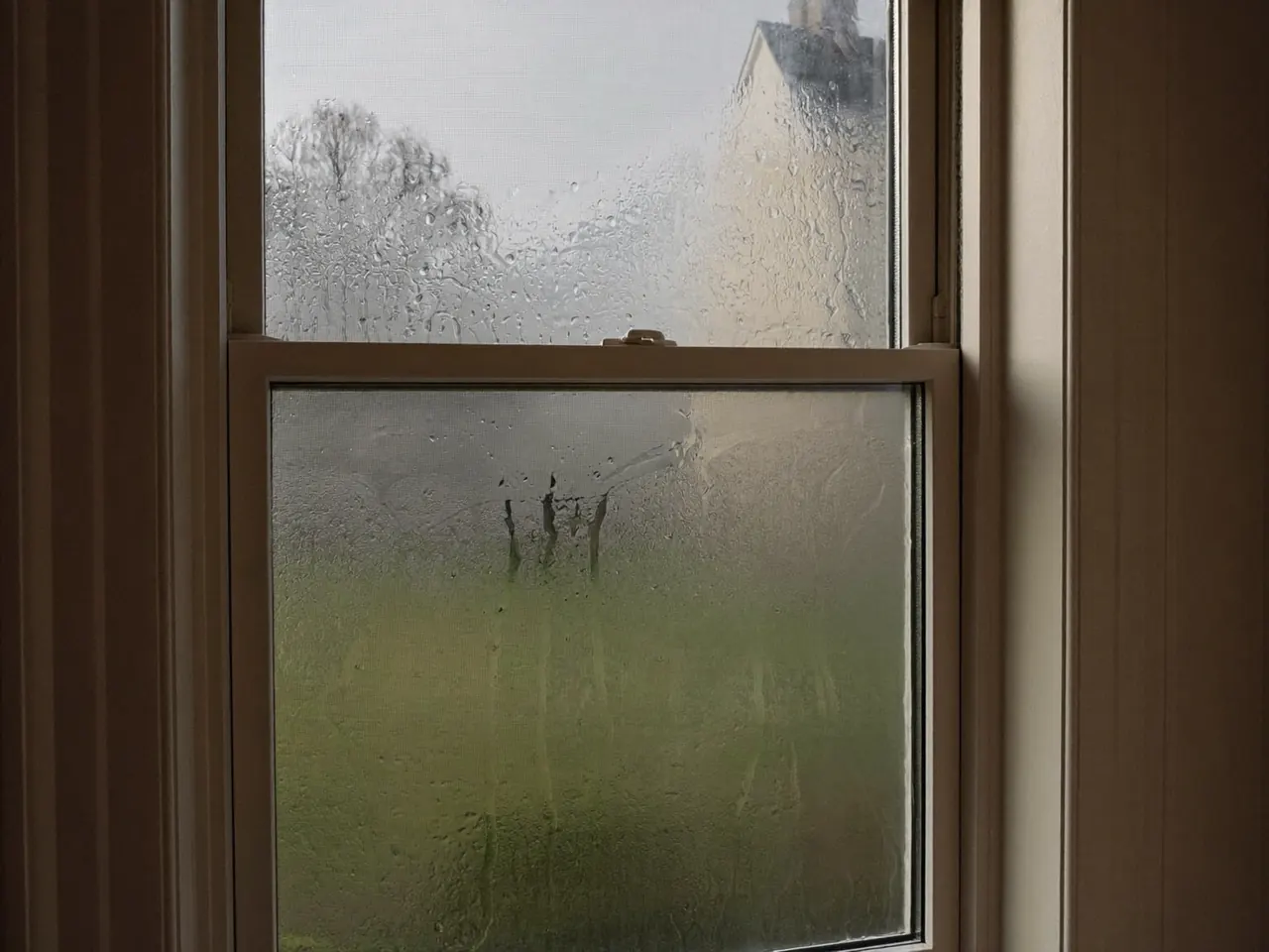 Condensation running down the inside surface of a home window on a cold morning