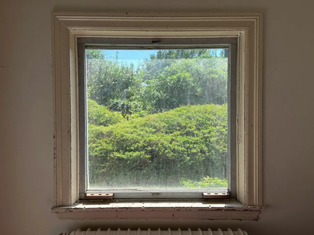 An older single-glazed window with a tired, weathered frame in a UK home